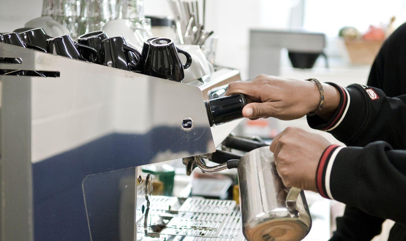 Person bereitet Kaffee an einer Siebträgermaschine zu