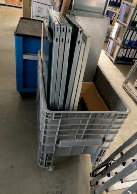 Elektroschrott-Abgabe im ZfW Frankfurt Große graue Kunststoffbox auf Rollen steht in einem Lagerraum. Darin befinden sich mehrere Metallteile und vermutlich ausrangierte Gerätegehäuse. Im Hintergrund sind Regale mit Aktenordnern zu sehen.