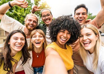 Angebote für Jugendliche im Zentrum für Weiterbildung Gruppe junger Menschen unterschiedlicher Herkunft lacht fröhlich in die Kamera bei einem Selfie im Freien.