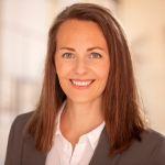 Dr. Nadja Martin-Catherin – Porträt Porträt einer lächelnden Frau mit schulterlangem braunem Haar im Business-Outfit. Sie trägt ein graues Sakko über einer weißen Bluse und blickt freundlich in die Kamera.