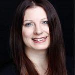 Veronika Moser – Zentrum für Weiterbildung Veronika Moser - Porträt einer Frau mit langen, glatten, dunkelbraunen Haaren und schwarzem Oberteil vor schwarzem Hintergrund, freundlich lächelnd.