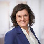 Porträt von Franziska Schuster, der Bildungscoachin in Darmstadt. Sie hat kurzes gewelltes braunes Haar, trägt eine Brille sowie einen blauen Blazer und eine weiße Bluse.